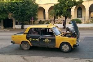 This is an older style state taxi in Cuba. As you can see from the photo, these taxis often require unscheduled maintenance. The drivers get to know these cars very well, and most minor repairs are done on the fly. These taxis are slow, bumpy, and they lack some of the creature comforts of modern vehicles, such as seat belts and air conditioning. But they are very popular. They are still expensive by local standards, but they are cheaper to use than the newer style state taxis. You can easily hail one of these cars and get a trip across town for about 5CUC or less.