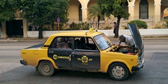 This is an older style state taxi in Cuba. As you can see from the photo, these taxis often require unscheduled maintenance. The drivers get to know these cars very well, and most minor repairs are done on the fly. These taxis are slow, bumpy, and they lack some of the creature comforts of modern vehicles, such as seat belts and air conditioning. But they are very popular. They are still expensive by local standards, but they are cheaper to use than the newer style state taxis. You can easily hail one of these cars and get a trip across town for about 5CUC or less.